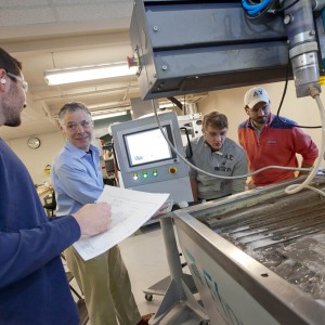 Prof. Scott Hummel works with students with the water jet cutter.
